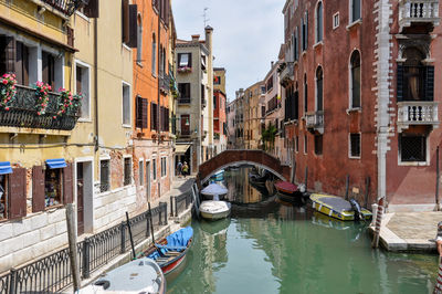 Boats moored in canal amidst buildings in city