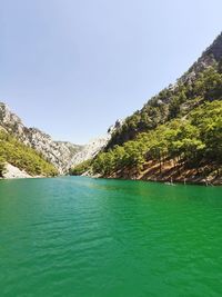 A lake in the mountains of emerald color, clear sky, green pine trees.