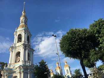 Low angle view of trees and building against blue sky