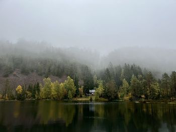 A cabin by a lake on a foggy morning.