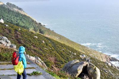 Pilgrim of the camino de santiago looking at the sea on the coast of death in finisterre, galicia