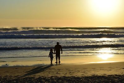 Silhouette woman walking at beach during sunset