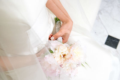 Midsection of bride holding bouquet