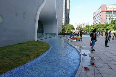 People walking on footpath in front of building