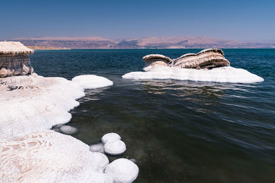 Rocks in sea against clear sky