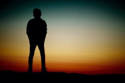 Silhouette man standing against orange sky