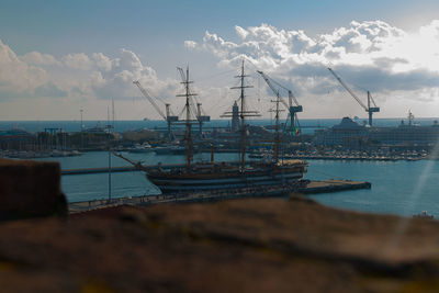 Sailboats moored at harbor against sky