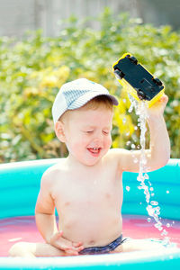 Little boy bathes in the pool on a hot day. sunny photo with a toddler. splashing water when bathing 