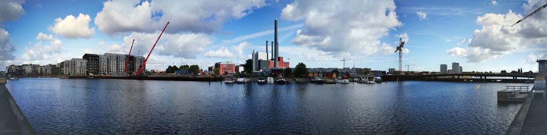 Panoramic view of buildings by river against sky
