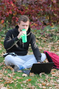 Full length of young man using mobile phone in field
