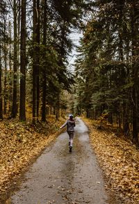 Rear view of man walking on road amidst trees