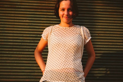 Portrait of a smiling young woman standing against wall