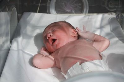 High angle view of baby lying on bed