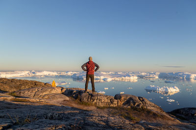 Man standing on rock against sky