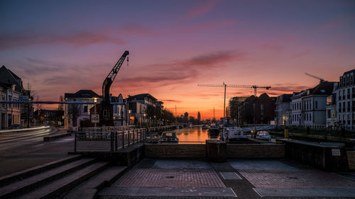 Illuminated buildings in city against sky at sunset
