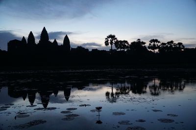 Silhouette of temple at lake during sunset