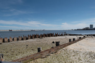 Wooden posts in sea against sky