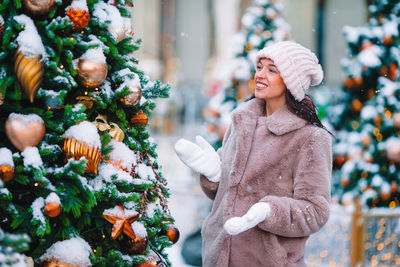 Midsection of woman standing by tree during winter