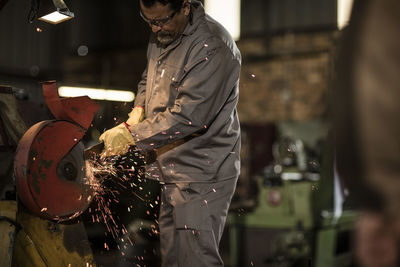 Metal worker using grinding machine in factory workshop