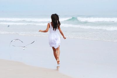 Rear view of woman jumping at beach