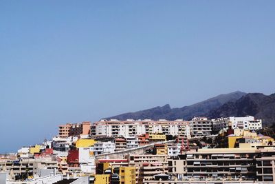 Houses in town against clear blue sky