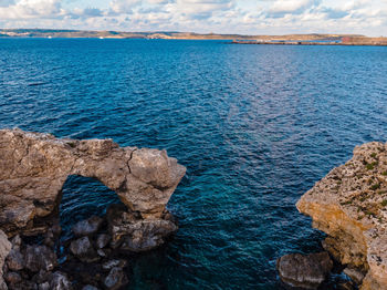 Rock formation in sea against sky