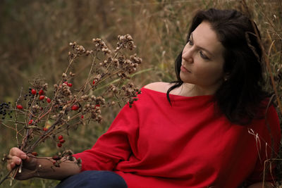 Beautiful woman sitting on red flowering plant