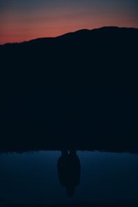 Reflection of people in water at sunset