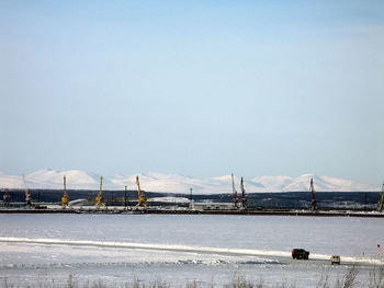 Bridge over river by snowcapped mountain against sky