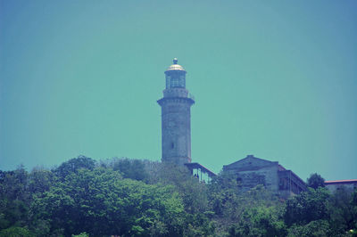 Low angle view of lighthouse by building against sky