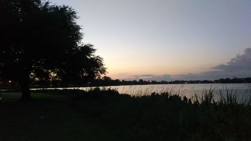 Silhouette trees by lake against sky during sunset