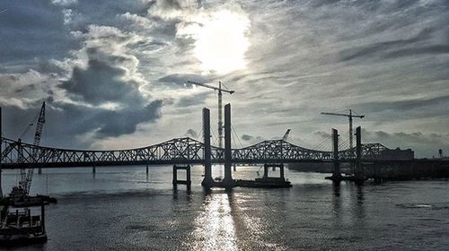 Bridge over river against cloudy sky