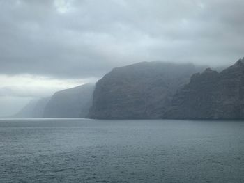 Scenic view of sea and mountains against sky