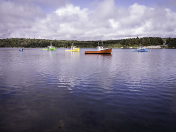 Boats in sea against cloudy sky