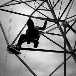 Low angle view of woman climbing rope against sky