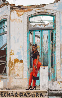 Full length of woman smiling while standing against entrance