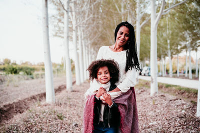 Portrait of smiling young woman with daughter outdoors