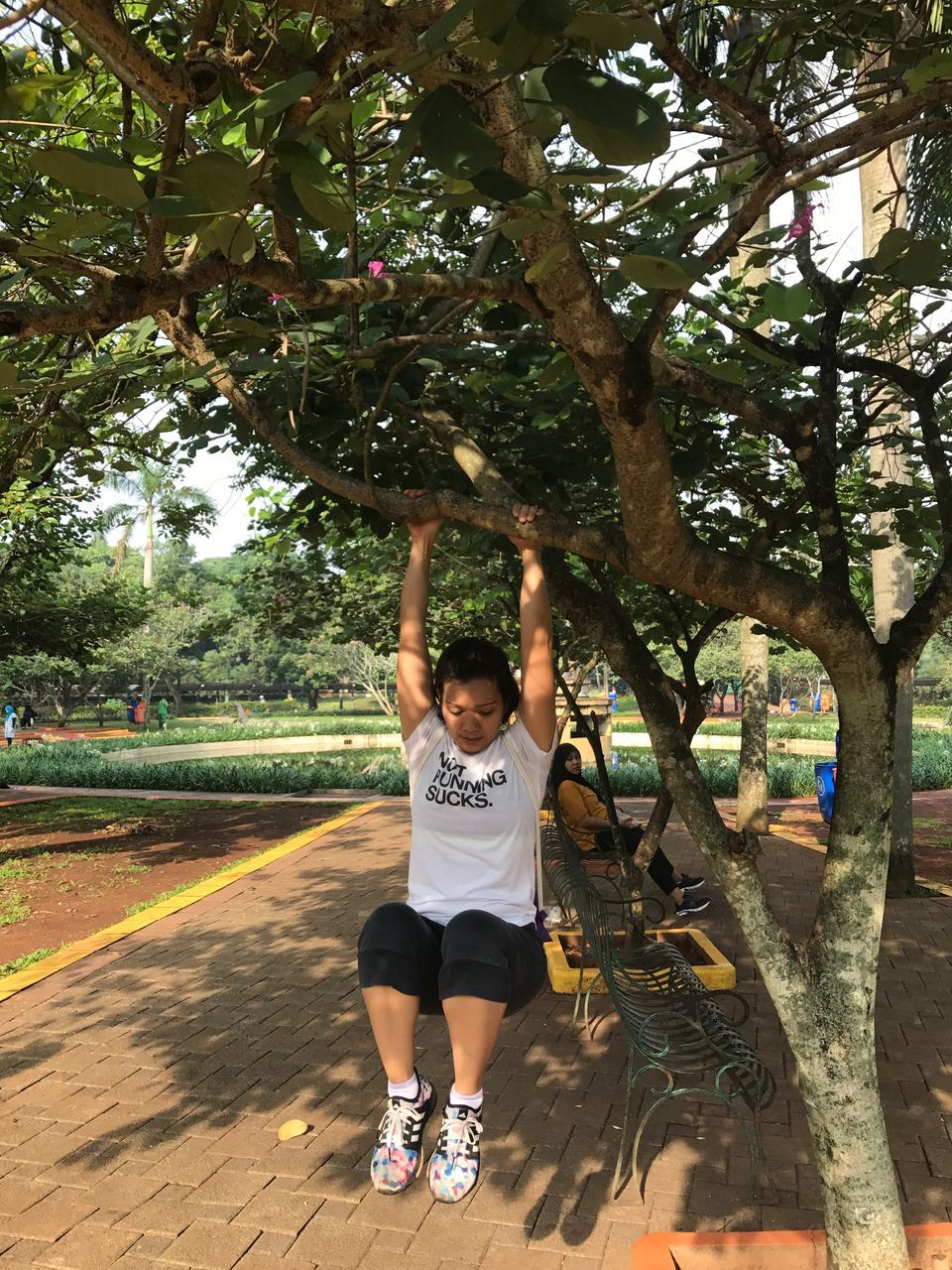 tree, real people, arms raised, leisure activity, one person, full length, lifestyles, casual clothing, front view, elementary age, day, park - man made space, childhood, young women, playing, boys, growth, happiness, outdoors, young adult, standing, branch, nature