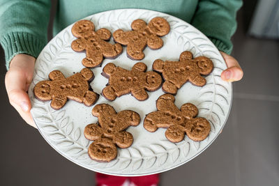 Midsection of boy holding gingerbread cookies at home