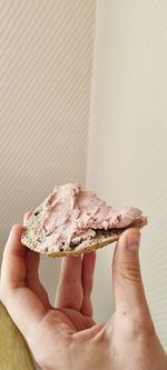 Close-up of hand holding ice cream against wall