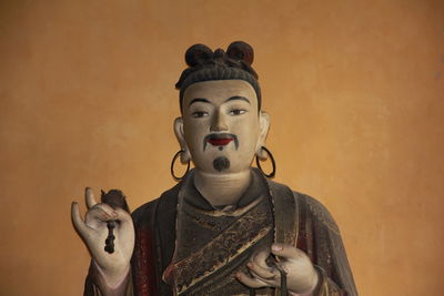 Close-up of buddha statue against wall