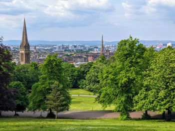 Trees and buildings in queen's park against sky