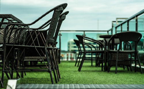 Empty chairs and tables in park against sky