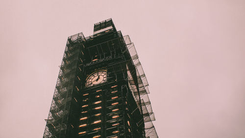 Low angle view of crane by building against clear sky