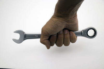 Close-up of hand holding cigarette against white background