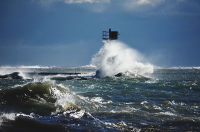 Waves breaking against sea against sky