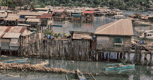 Boats moored in river with houses in background