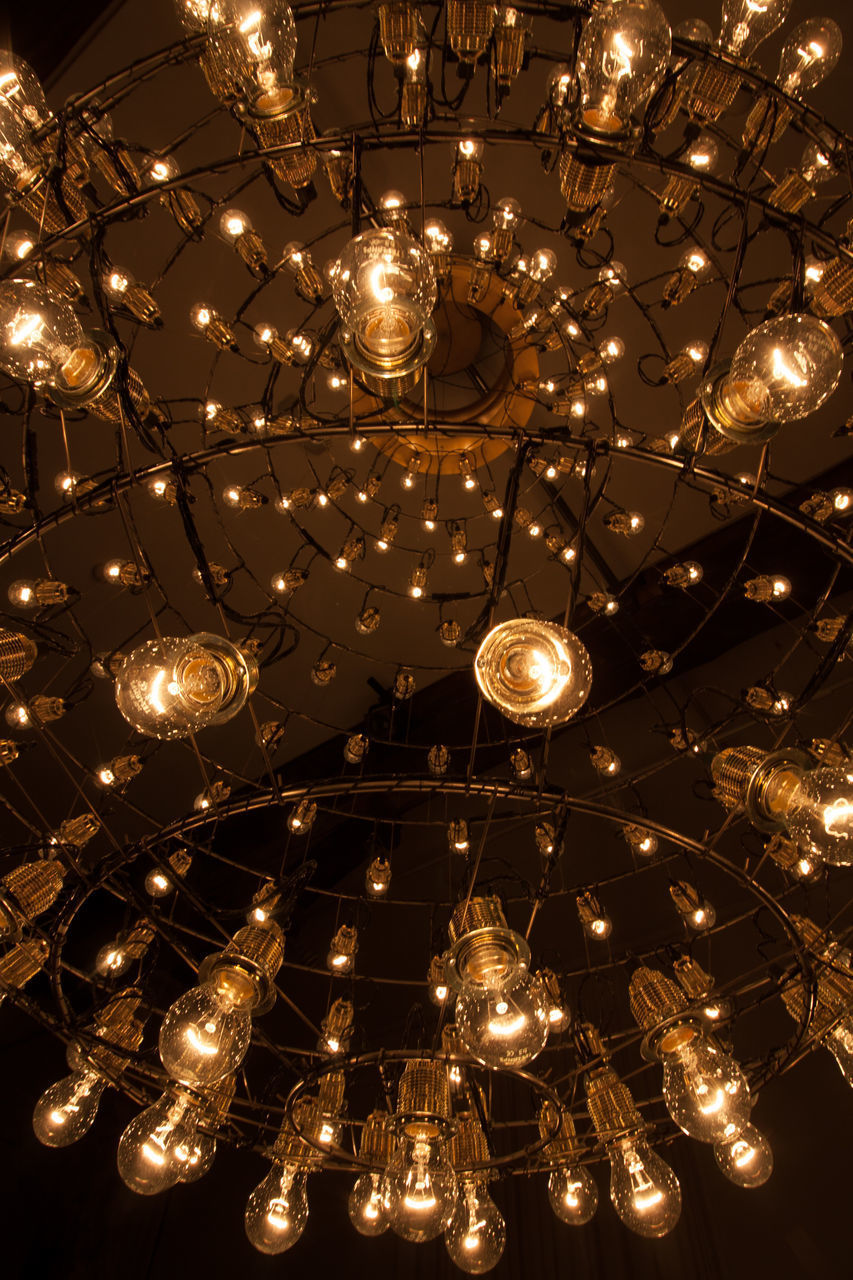 LOW ANGLE VIEW OF ILLUMINATED LIGHT BULB HANGING AT NIGHT