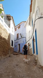 Rear view of man walking outside building against sky