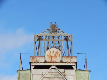 Low angle view of old rusty against blue sky